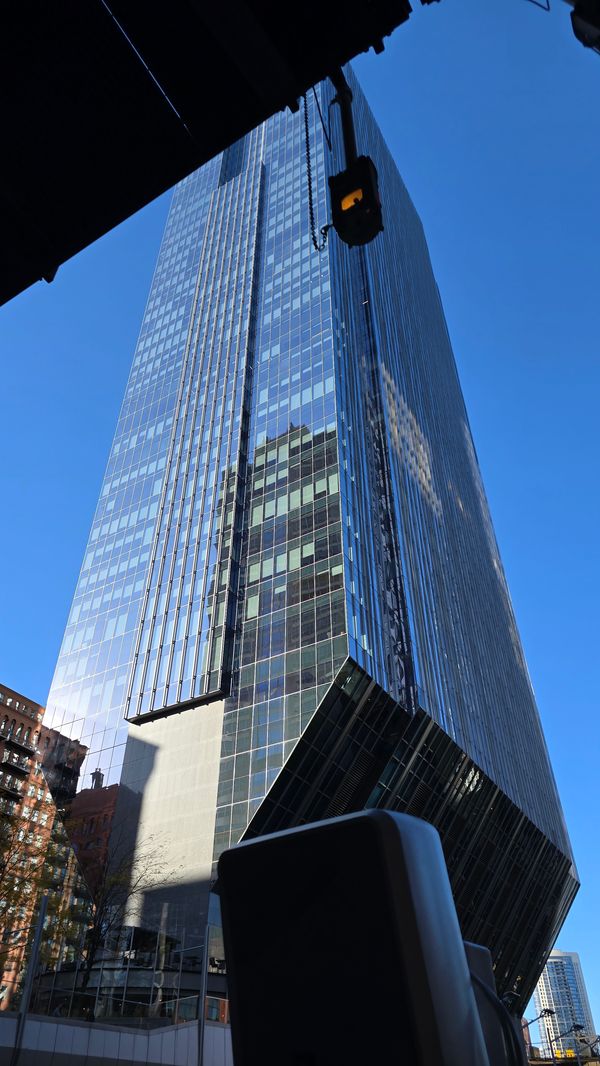 A large glass building with a narrow base shot from below.