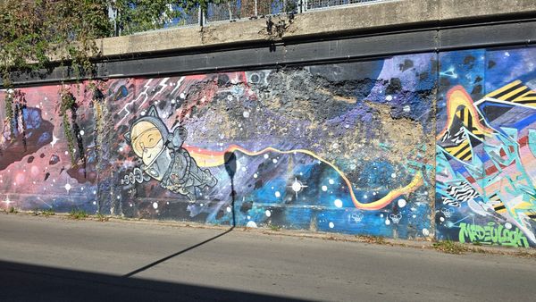 A large graffiti wall, with a space theme. On the left is a cartoon of a corgi in a spacesuit, holding a ray gun.