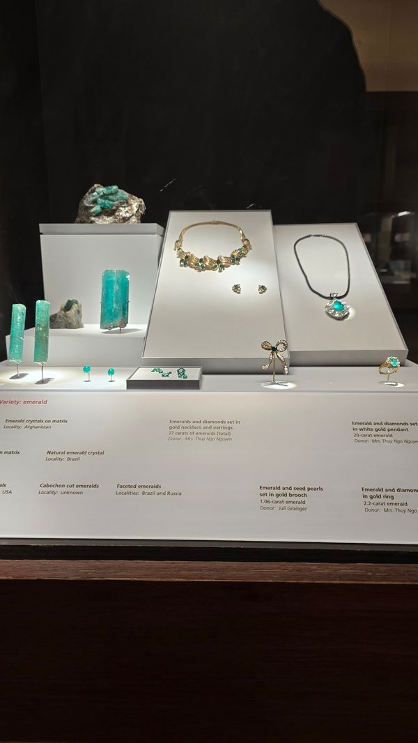 A display of several emerald gemstones, some set in jewelry