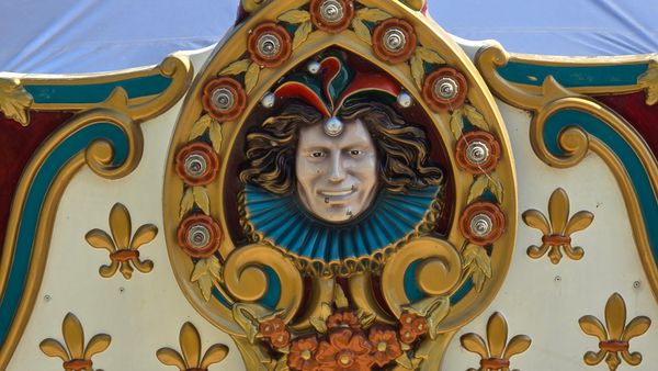 Detail of the carousel at Navy Pier, focusing on a dead-eyed jester's face carved into the top piece of the carousel.