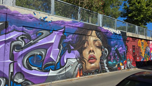 A graffiti wall, centered on a cyborg woman's head