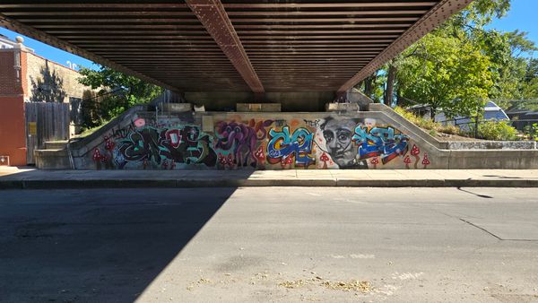 A graffiti wall under a footpath bridge